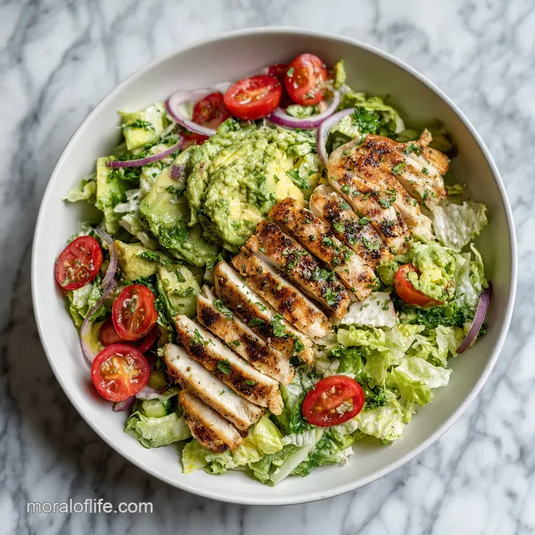 Neatly plated avocado chicken salad: pale green mixture contrasted with crisp greens and juicy red tomatoes, inviting and ...